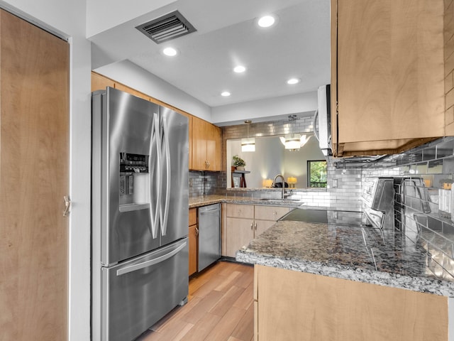 kitchen featuring light wood-style flooring, stainless steel appliances, a sink, visible vents, and tasteful backsplash