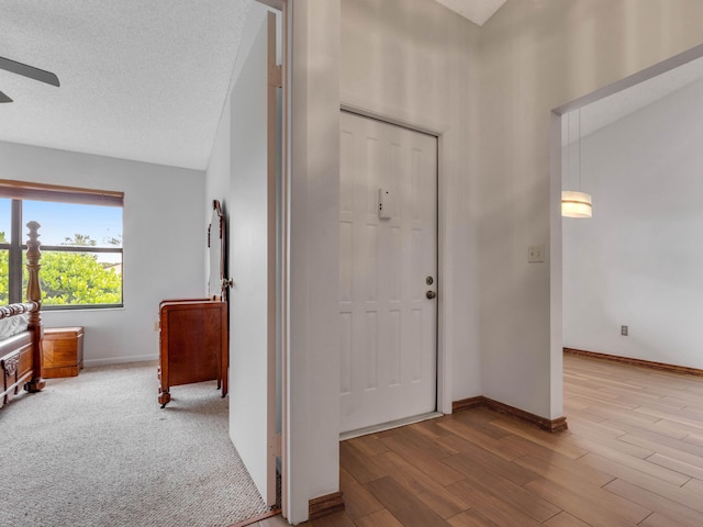 entryway featuring a textured ceiling, ceiling fan, wood finished floors, and baseboards