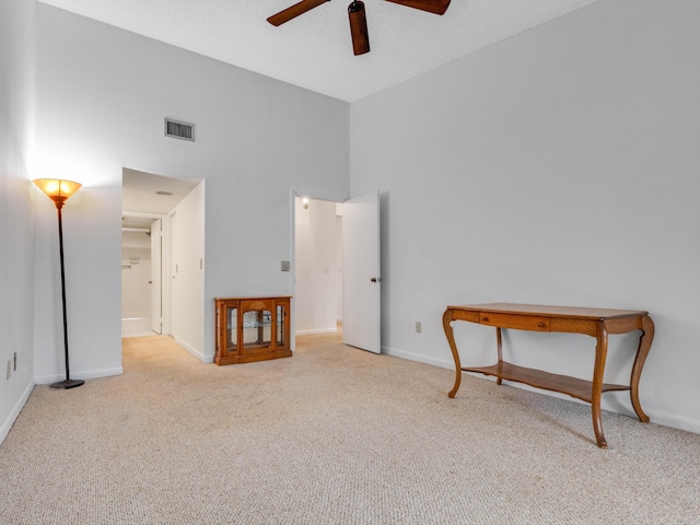 interior space with baseboards, a high ceiling, visible vents, and carpet flooring