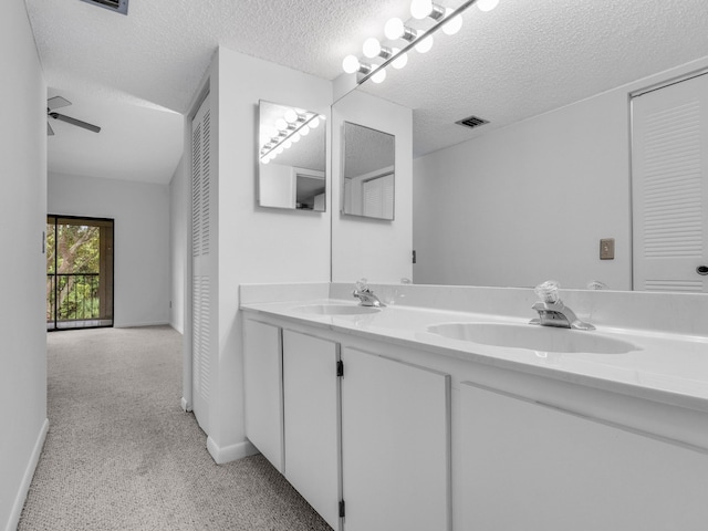 bathroom featuring visible vents, a sink, a textured ceiling, and double vanity