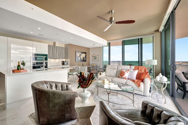 living room featuring ceiling fan, a wall of windows, and sink