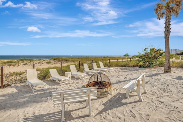 view of patio featuring a water view, an outdoor fire pit, and a view of the beach