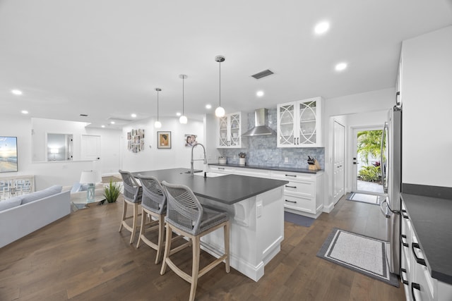 kitchen with a center island with sink, wall chimney range hood, sink, dark hardwood / wood-style flooring, and white cabinetry