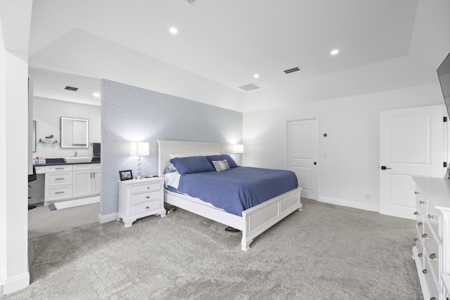 carpeted bedroom featuring connected bathroom and sink