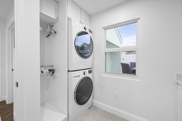 laundry area with cabinets and stacked washing maching and dryer