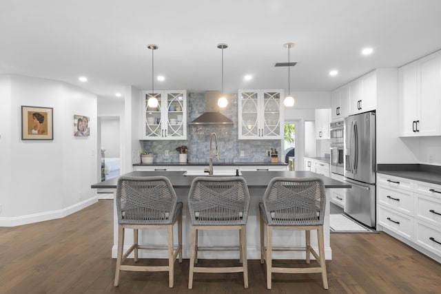 kitchen with appliances with stainless steel finishes, dark hardwood / wood-style flooring, white cabinetry, and an island with sink