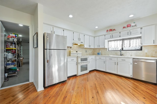 kitchen with stainless steel appliances, sink, white cabinets, and light wood-type flooring