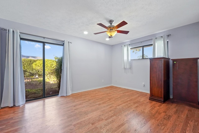 spare room with hardwood / wood-style flooring, plenty of natural light, and a textured ceiling