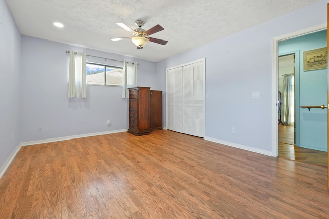 unfurnished bedroom featuring ceiling fan, a textured ceiling, light hardwood / wood-style floors, and a closet