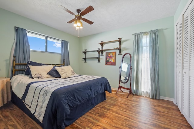 bedroom featuring ceiling fan, a closet, dark hardwood / wood-style flooring, and a textured ceiling