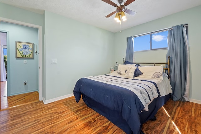 bedroom featuring ceiling fan, hardwood / wood-style floors, and a textured ceiling