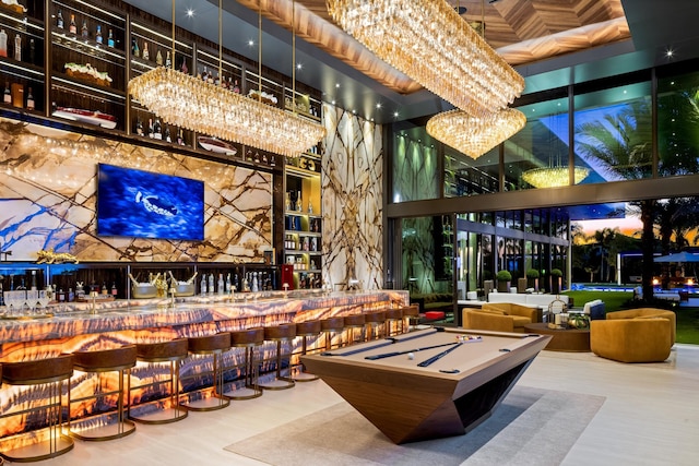 rec room featuring a chandelier, bar area, a towering ceiling, and pool table