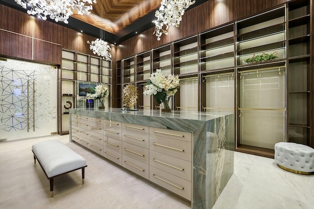 walk in closet featuring beamed ceiling, a towering ceiling, and a notable chandelier