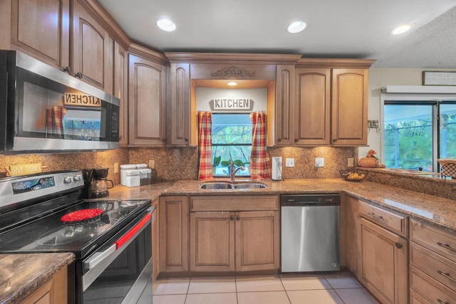 kitchen featuring tasteful backsplash, dark stone counters, stainless steel appliances, sink, and light tile patterned floors