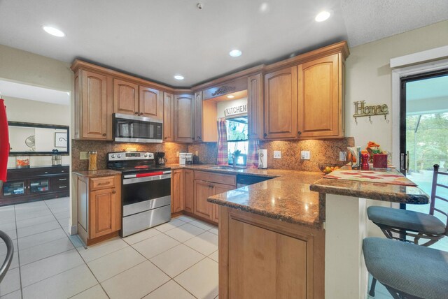 kitchen with sink, a kitchen breakfast bar, tasteful backsplash, kitchen peninsula, and appliances with stainless steel finishes