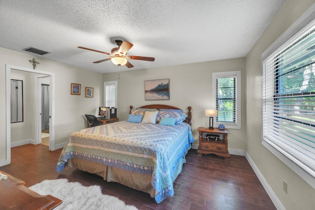 bedroom featuring ceiling fan, dark hardwood / wood-style flooring, and a textured ceiling