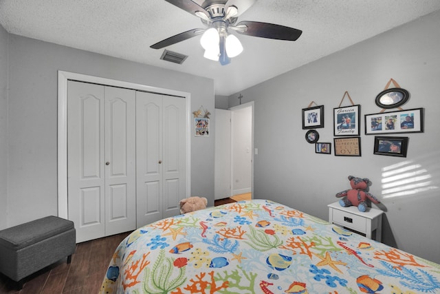 bedroom featuring a textured ceiling, dark hardwood / wood-style floors, a closet, and ceiling fan