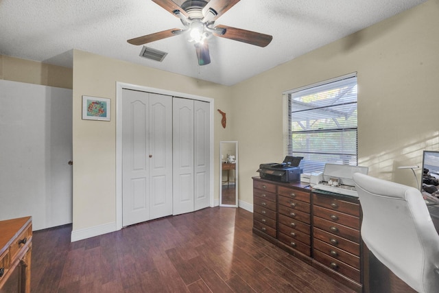 office featuring a textured ceiling, ceiling fan, and dark wood-type flooring