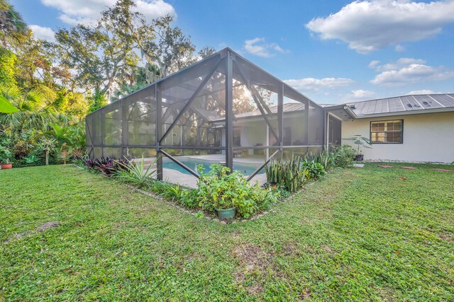 back of property with a yard and glass enclosure