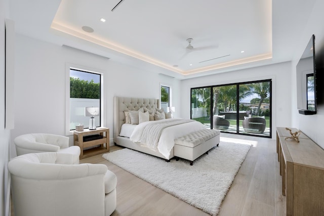 bedroom with access to outside, a raised ceiling, multiple windows, and ceiling fan