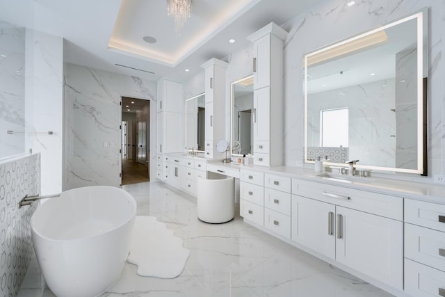 bathroom featuring a tray ceiling, a washtub, vanity, and tile walls