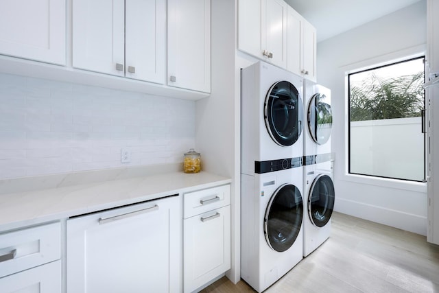 laundry room with cabinets, light hardwood / wood-style flooring, and stacked washer / drying machine