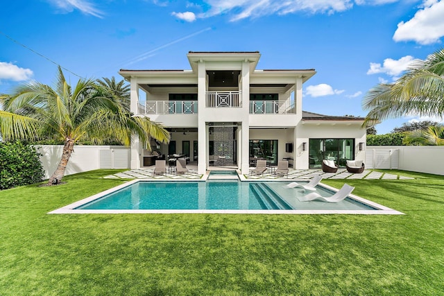 rear view of house featuring a lawn, ceiling fan, a balcony, a fenced in pool, and a patio area