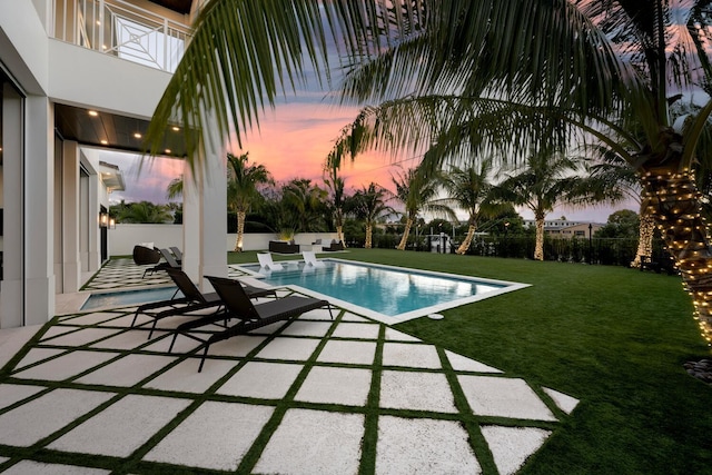 pool at dusk with a yard and a patio