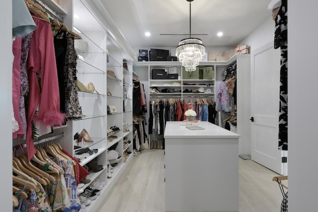 spacious closet featuring a notable chandelier and light hardwood / wood-style floors