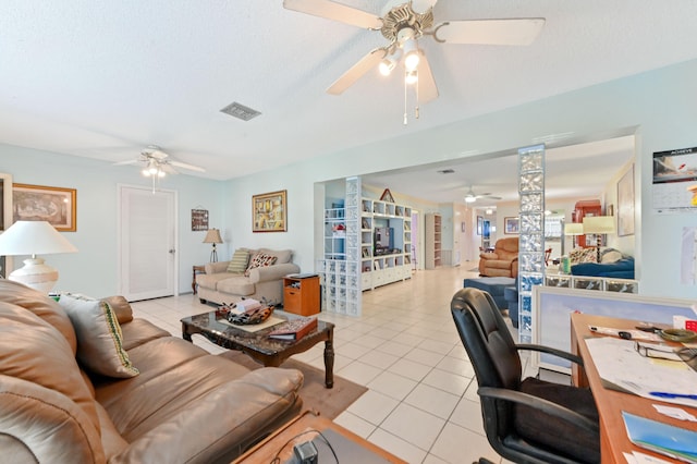 living room featuring ceiling fan, light tile patterned floors, and a textured ceiling