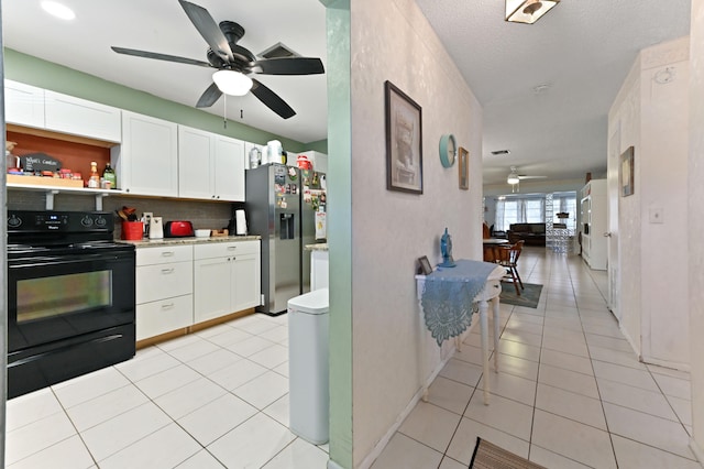 kitchen featuring stainless steel fridge, backsplash, black / electric stove, white cabinets, and light tile patterned floors