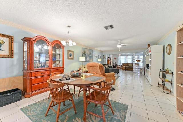 tiled dining area featuring ceiling fan with notable chandelier and a textured ceiling