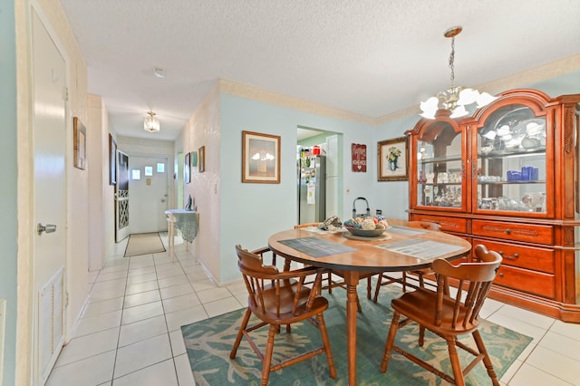 dining room with a chandelier, a textured ceiling, and light tile patterned flooring