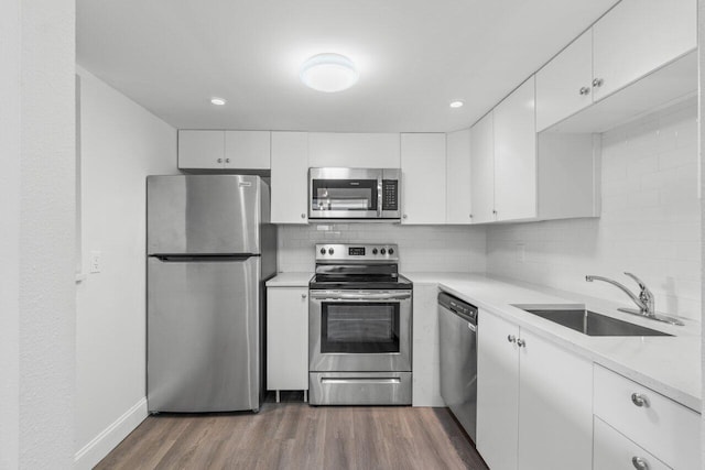 kitchen with sink, appliances with stainless steel finishes, tasteful backsplash, white cabinetry, and wood-type flooring