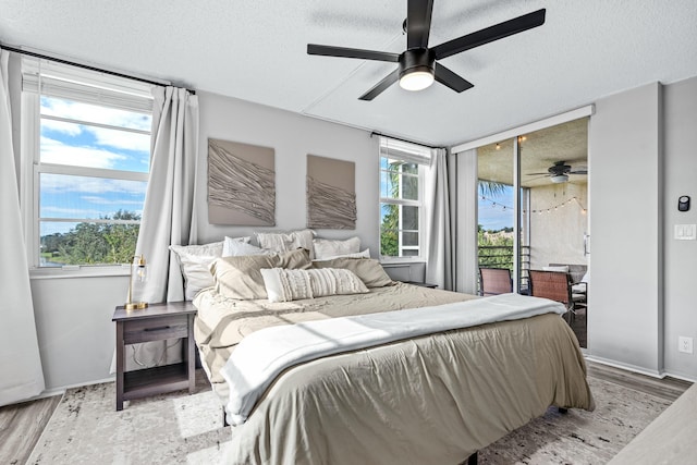 bedroom with multiple windows, ceiling fan, light hardwood / wood-style floors, and a textured ceiling