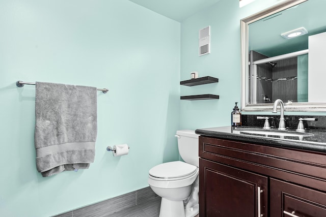 bathroom with tile patterned flooring, a shower with door, vanity, and toilet