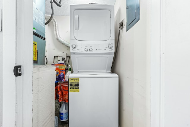 laundry room with electric panel and stacked washer and clothes dryer