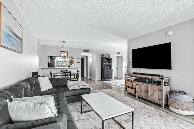 living room featuring hardwood / wood-style floors, a textured ceiling, and an inviting chandelier