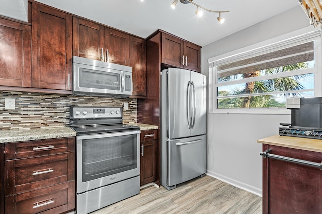 kitchen featuring backsplash, stainless steel appliances, light hardwood / wood-style flooring, and light stone counters