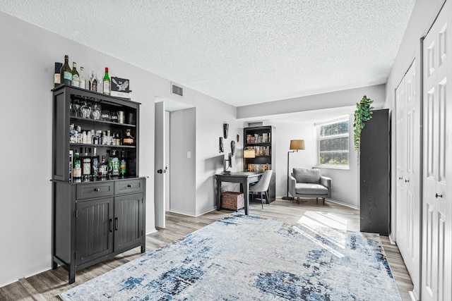 interior space featuring hardwood / wood-style flooring, a textured ceiling, and bar area