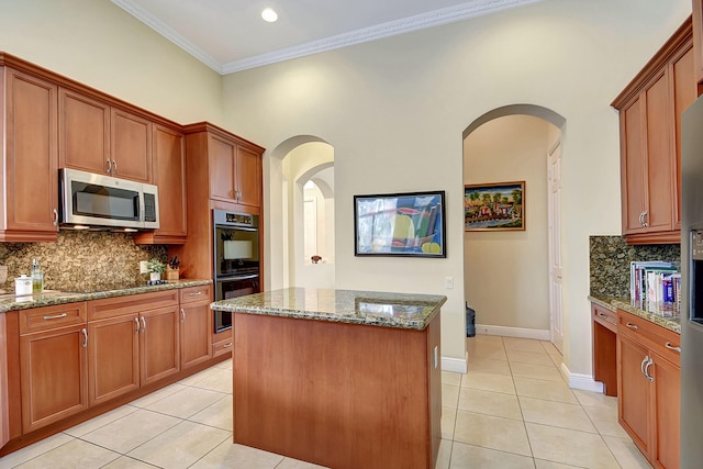 kitchen with light stone countertops, ornamental molding, black appliances, a kitchen island, and light tile patterned flooring