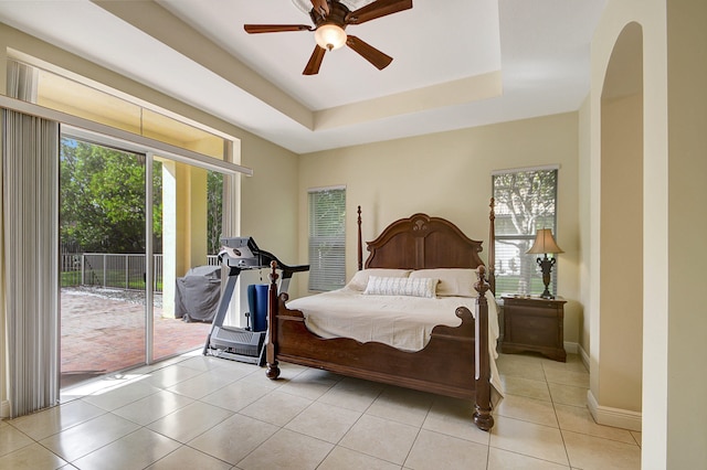 bedroom featuring access to outside, ceiling fan, a tray ceiling, and light tile patterned flooring