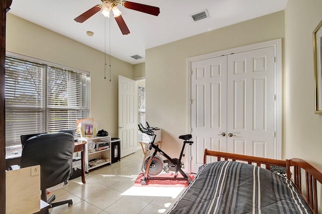 tiled bedroom with ceiling fan and a closet