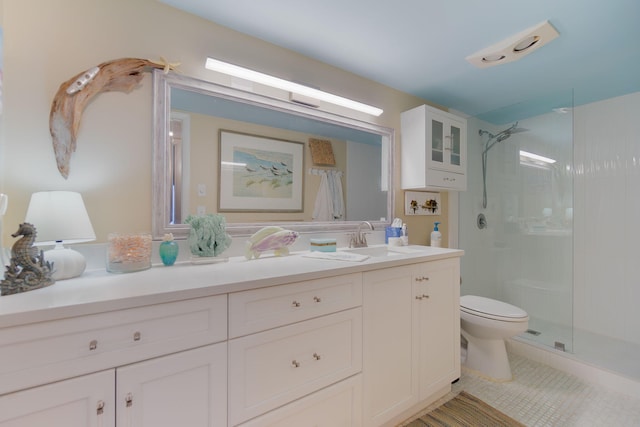 bathroom featuring a tile shower, tile patterned flooring, vanity, and toilet