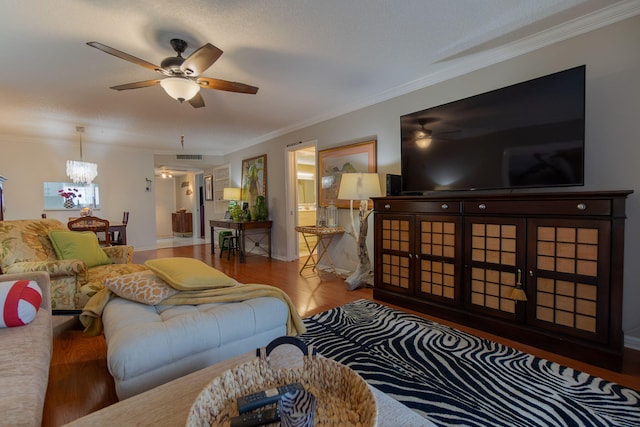 living room featuring wood-type flooring, ceiling fan with notable chandelier, and crown molding