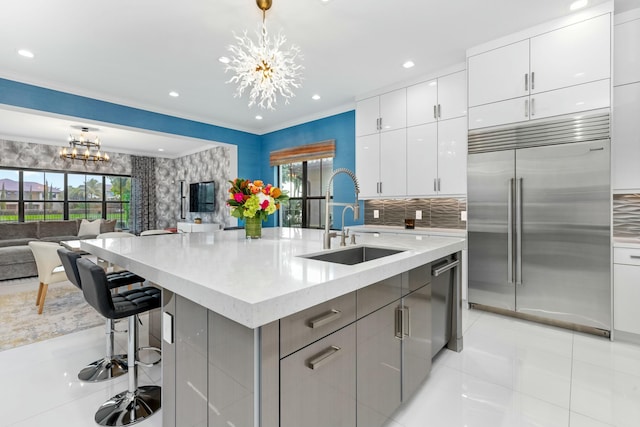 kitchen featuring sink, an inviting chandelier, decorative light fixtures, appliances with stainless steel finishes, and an island with sink