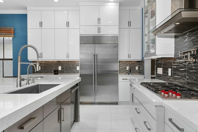 kitchen featuring stainless steel appliances, light stone countertops, exhaust hood, and white cabinets