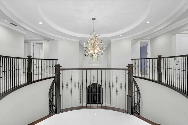 hallway featuring an inviting chandelier, crown molding, and a raised ceiling