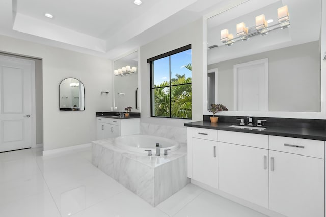 bathroom with a raised ceiling, vanity, tile patterned flooring, and tiled tub