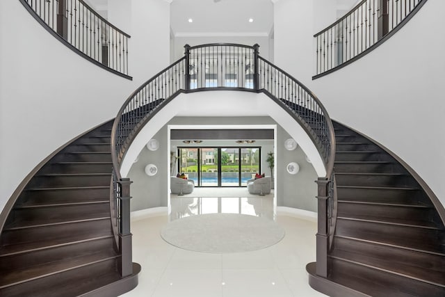 entryway featuring crown molding, a towering ceiling, and tile patterned flooring